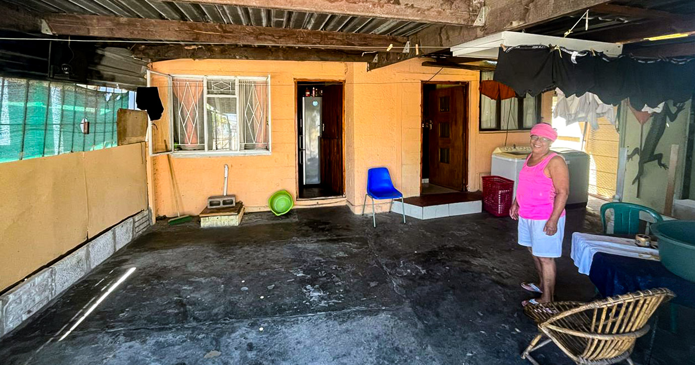 A roofed backyard of a small host family home with a smiling host mother.