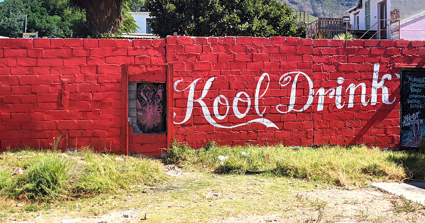 A "Kool Drink" graffiti in Coca-Cola style on a red-painted wall in Cape Town.