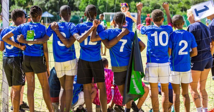 Arm in Arm posiert eine Kinder- und Jugendsportmannschaft vor einem Tor für ein Foto.